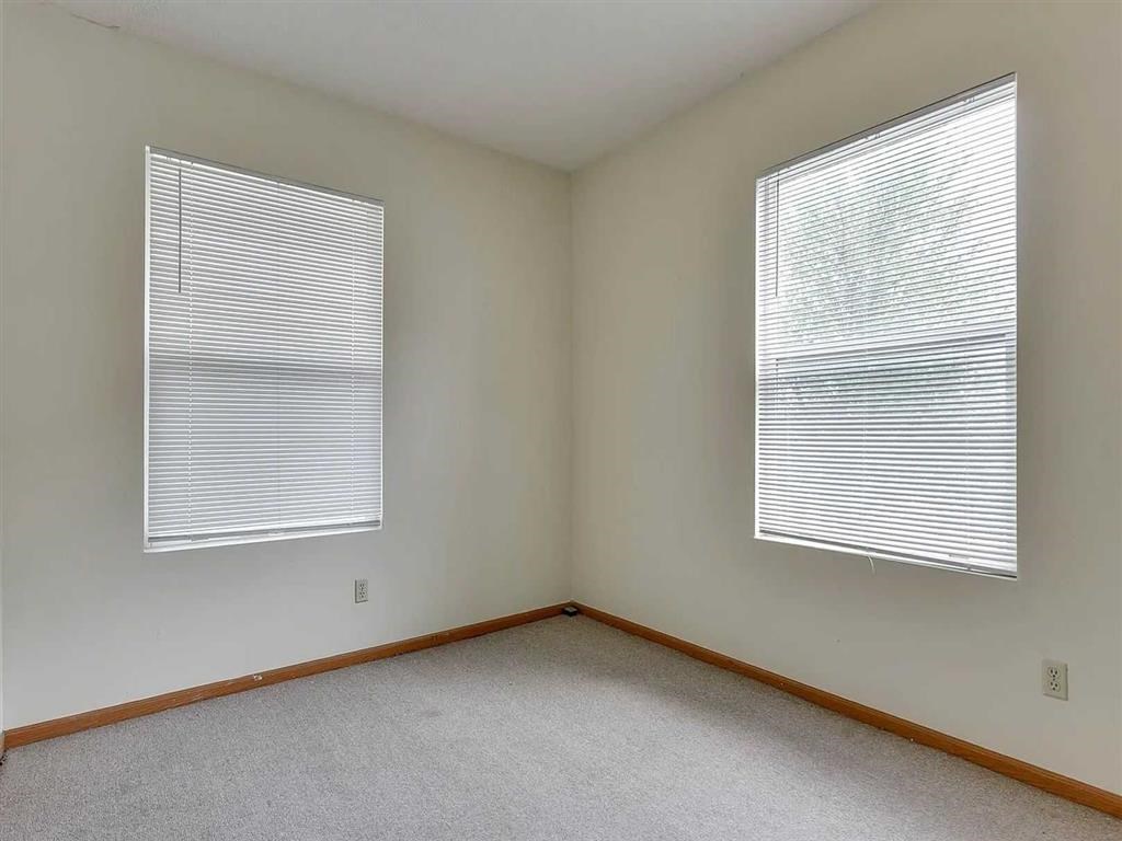 A room with two windows covered in blinds.