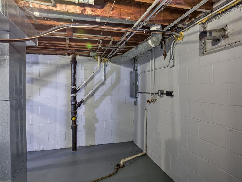 A room with a white wall and a brown pipe.