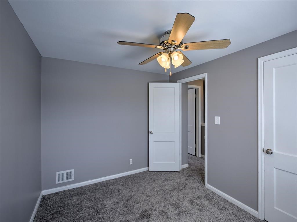 A room with a ceiling fan and carpeted floor.