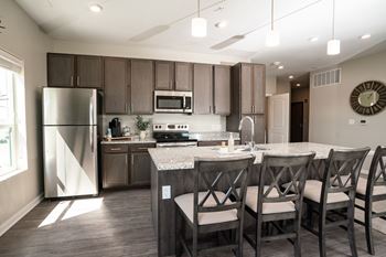A modern kitchen with a refrigerator, microwave, oven, and sink.
