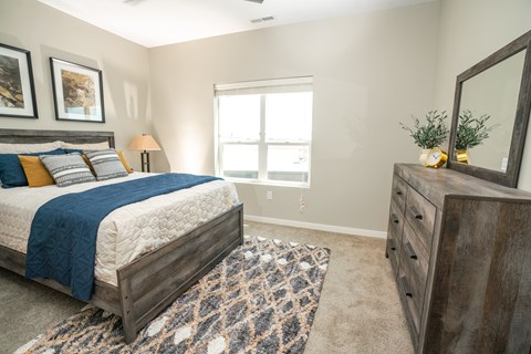 A bedroom with a bed, dresser, and window.