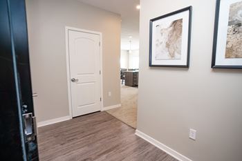 A hallway with a white door and two framed pictures on the wall.