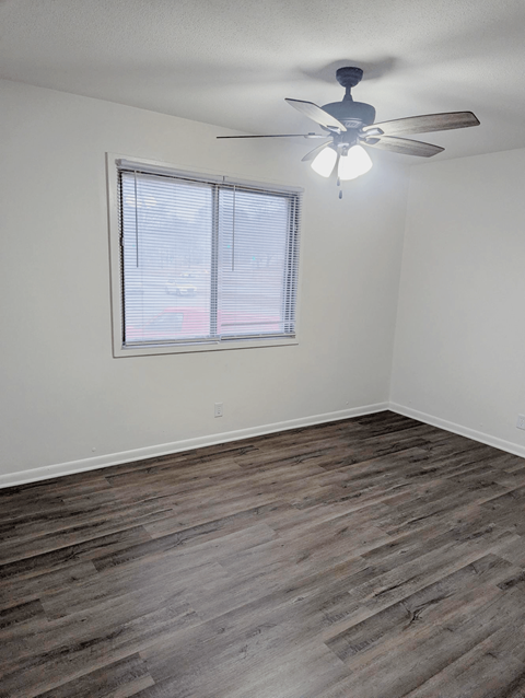 Bedroom with wood style flooring ceiling fan and window at Northbrook Apartments