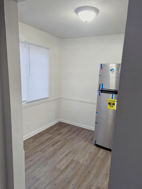 Dining area with wood style flooring and a window near the kitchen at Northbrook Apartments