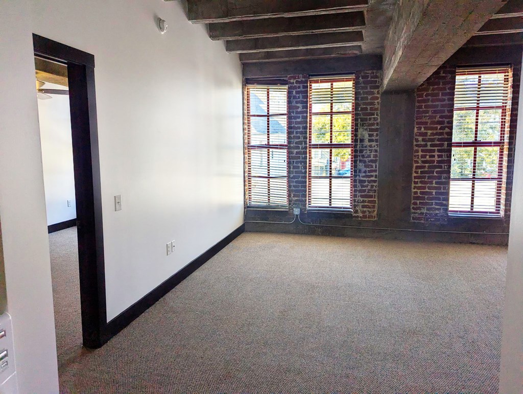 A room with a carpeted floor and a brick wall.