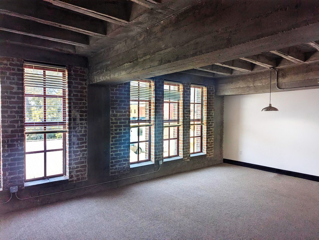 A room with a concrete ceiling and brick walls with windows.