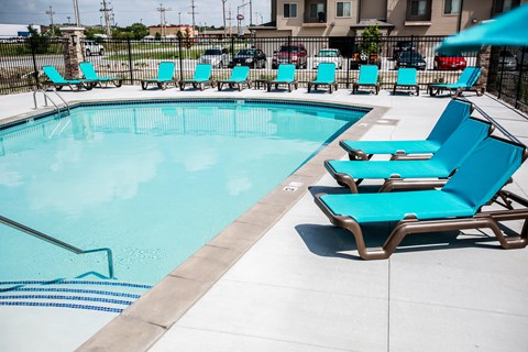 A pool with blue chairs and a white fence.
