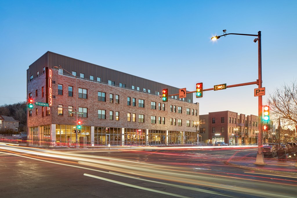 A long exposure shot of a street with a red traffic light and a building in the background.