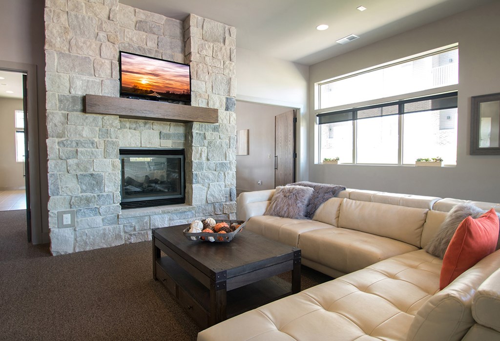 A living room with a stone fireplace and a flat screen TV mounted above it.