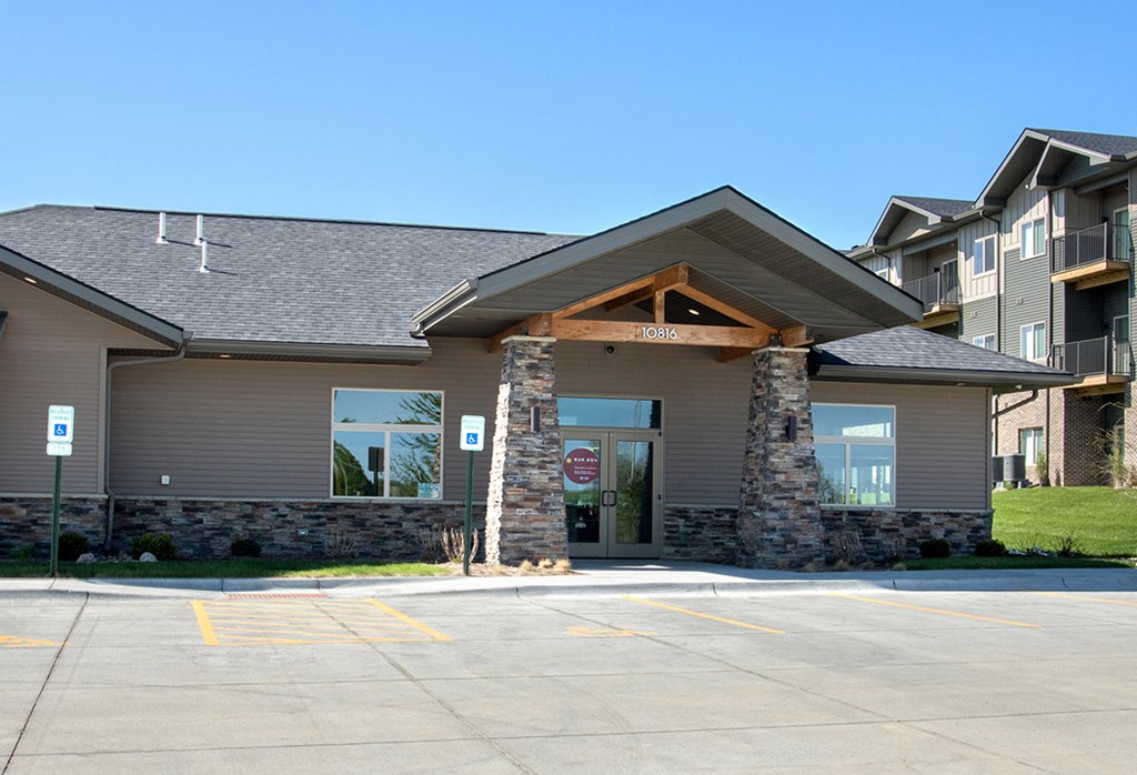 A building with a stone pillar entrance and a parking lot in front.