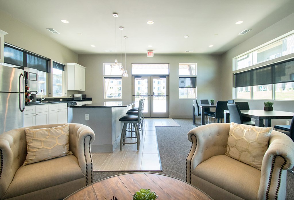 A modern kitchen with a dining area and two beige armchairs.