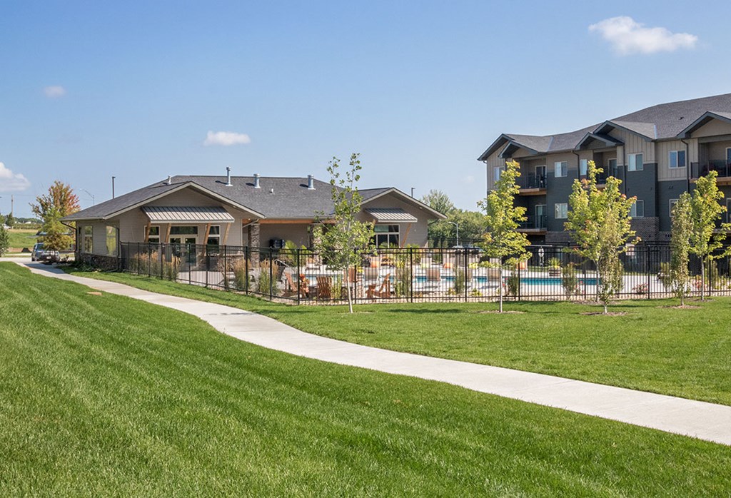 A grassy area in front of a building with a pool.
