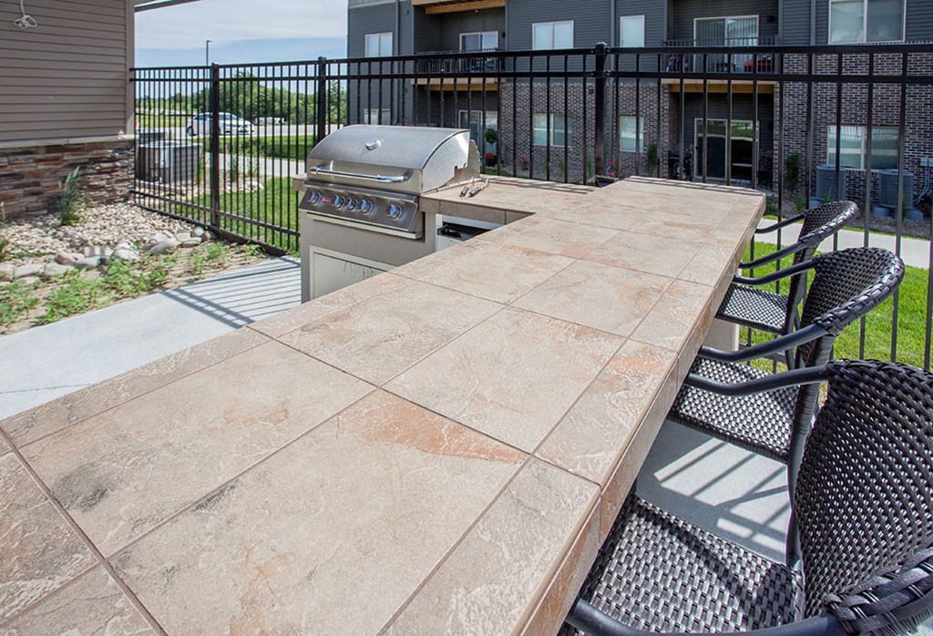 A patio with a table and chairs and a grill.