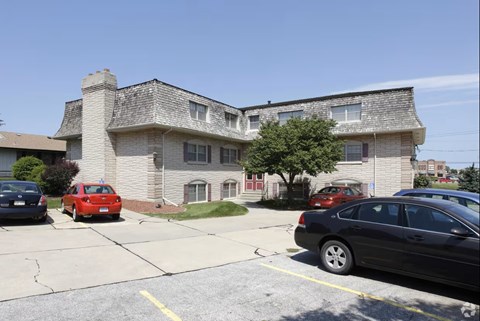 A black car is parked in a parking lot in front of a building.