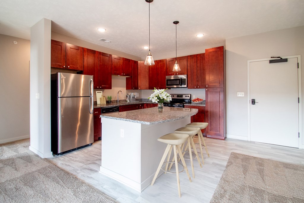 A kitchen with a white island and wooden stools.
