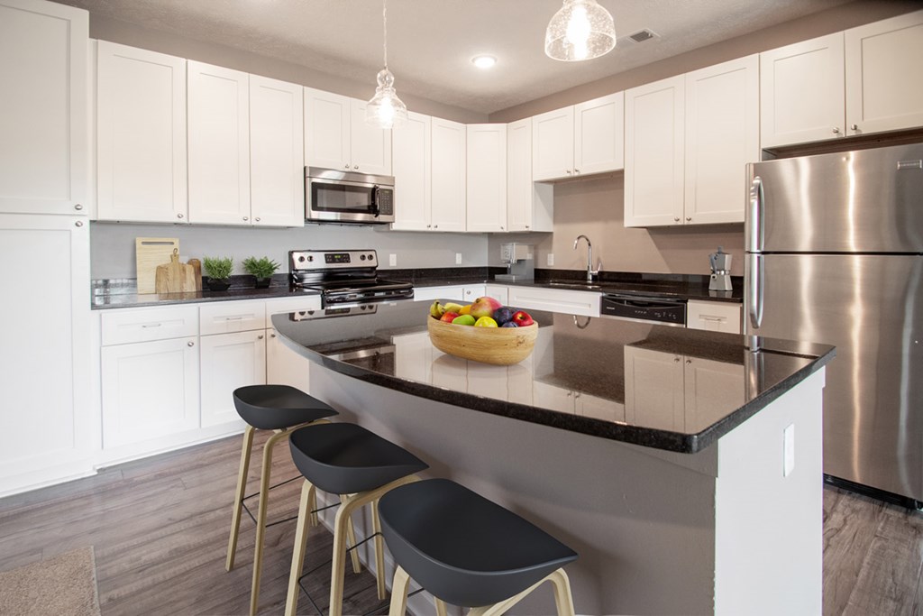 A kitchen with a black countertop and white cabinets.