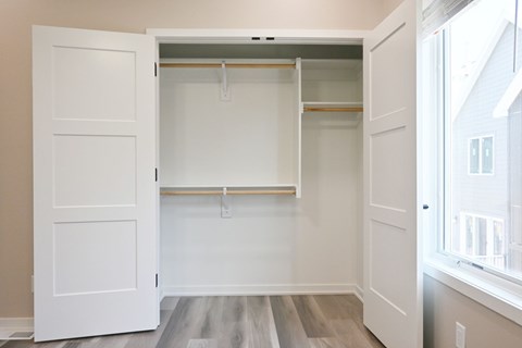 A white closet with a shelf and a white door.