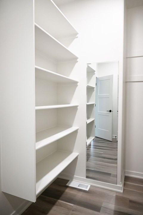 A hallway with a white door and shelves on the side.