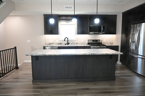 A kitchen with a marble countertop and dark wood cabinets.
