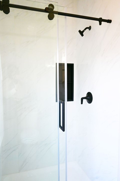 A black shower door handle with a black lever.