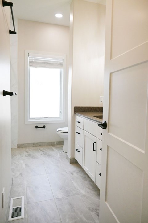 A bathroom with a toilet, sink, and window.