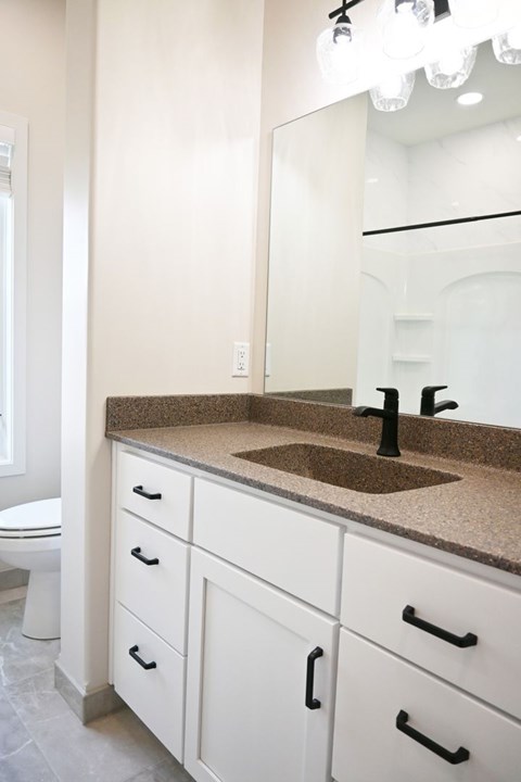 A bathroom with a sink, mirror, and toilet.