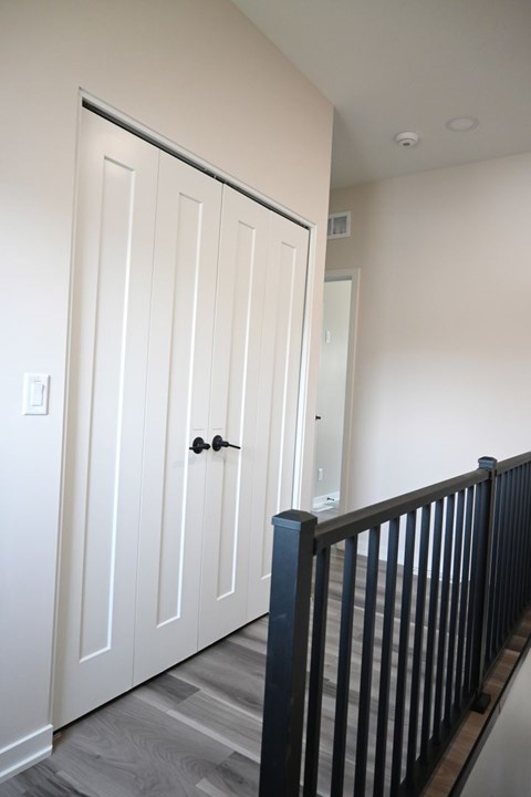 A white door with a black handle is in a room with a black railing.