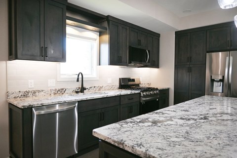 A kitchen with black cabinets and granite countertops.