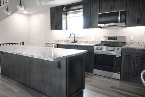 A kitchen with a marble countertop and dark wood cabinets.