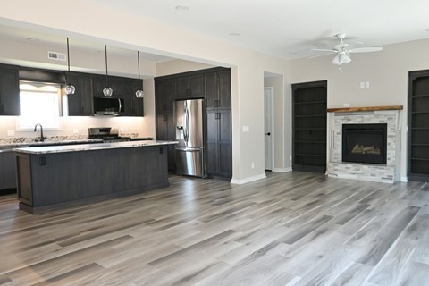 A modern kitchen with dark wood floors and a fireplace.
