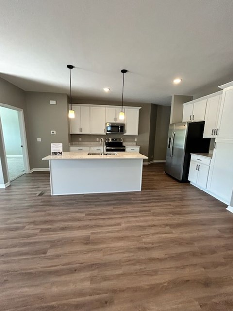 A kitchen with a white island and wooden floors.