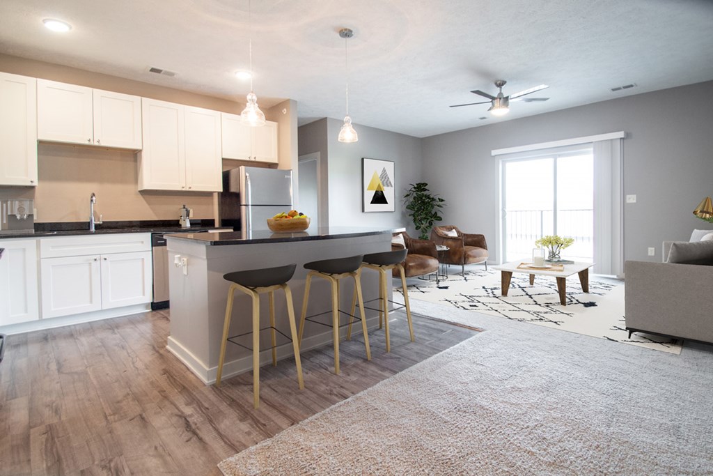 A kitchen with a bar and stools in front of it.