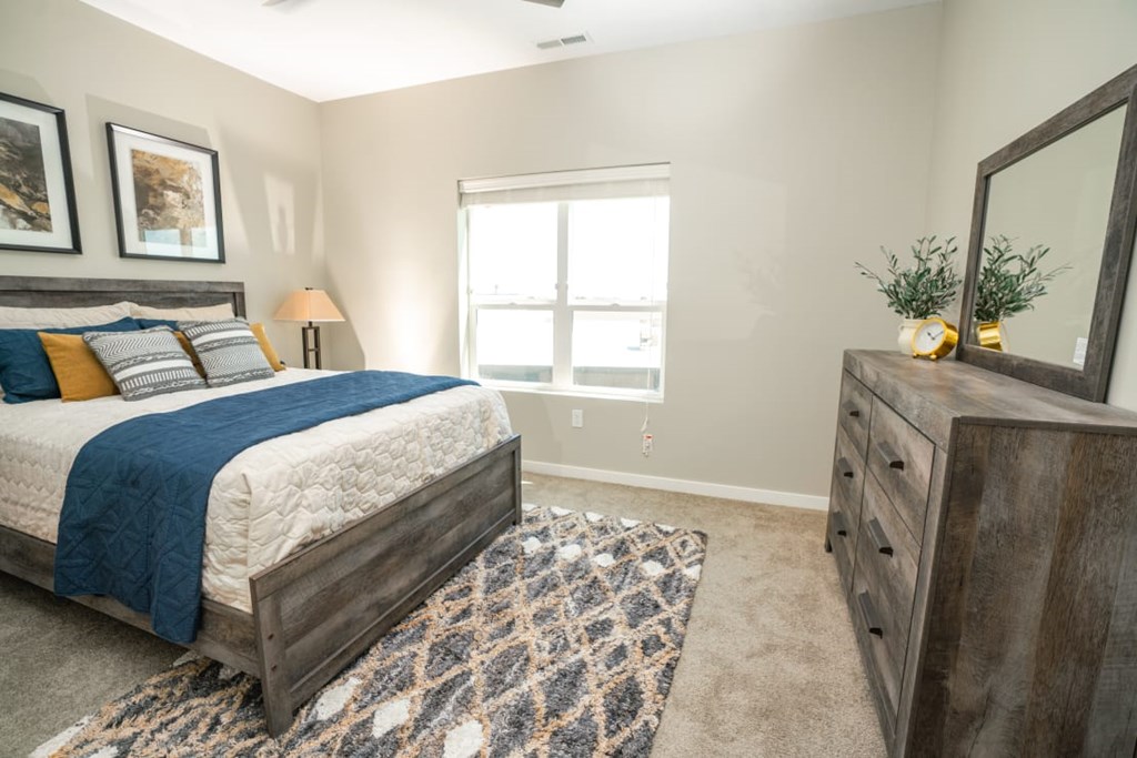 A bedroom with a bed, dresser, and window.