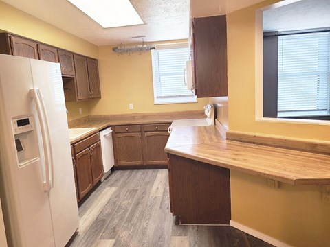 A kitchen with a white refrigerator and wooden cabinets.