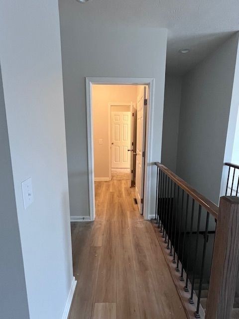A hallway with a black railing and wooden floors.