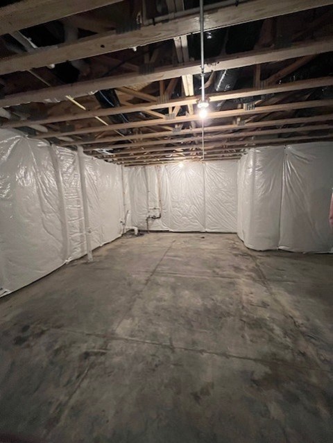 A room with a white ceiling and walls, covered in plastic, with wooden beams on the ceiling.