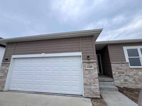 A house with a white garage door and the number 21209 on the front door.