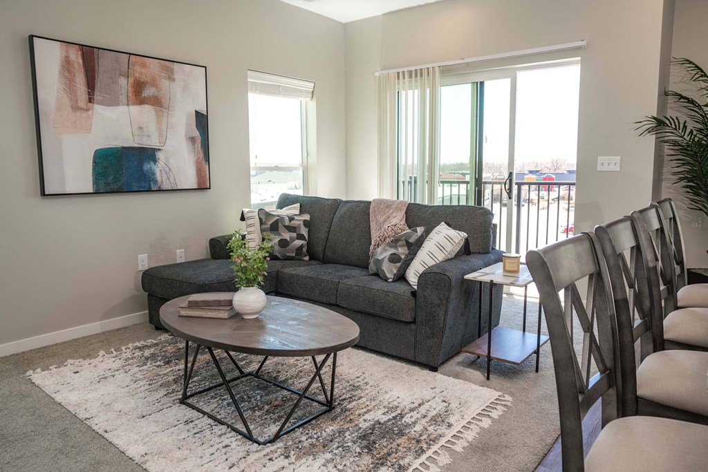A living room with a grey couch, a coffee table, and a painting on the wall.