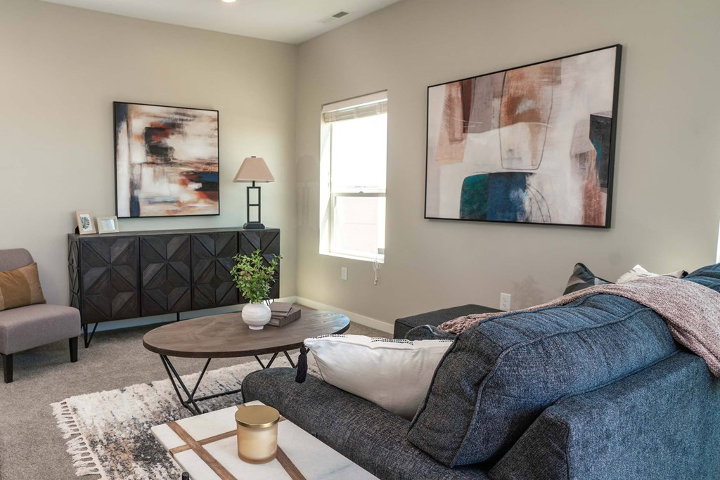 A living room with a grey couch, a coffee table, and a painting on the wall.