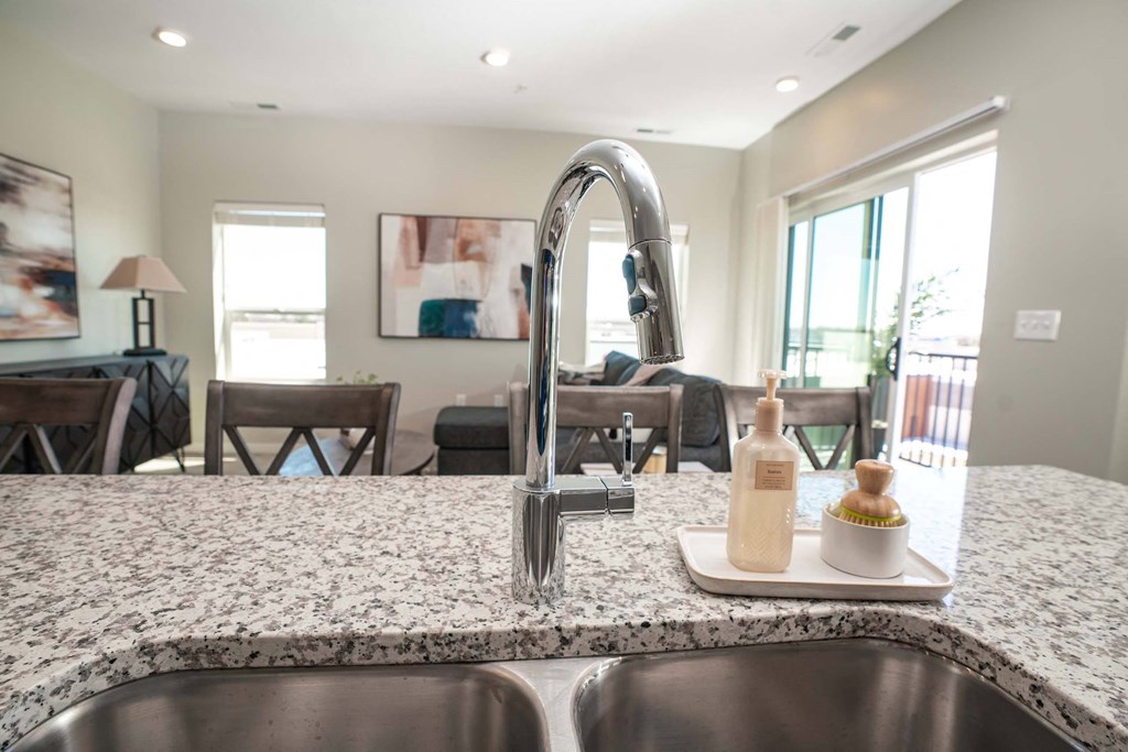 A modern kitchen with a granite countertop and stainless steel sink.