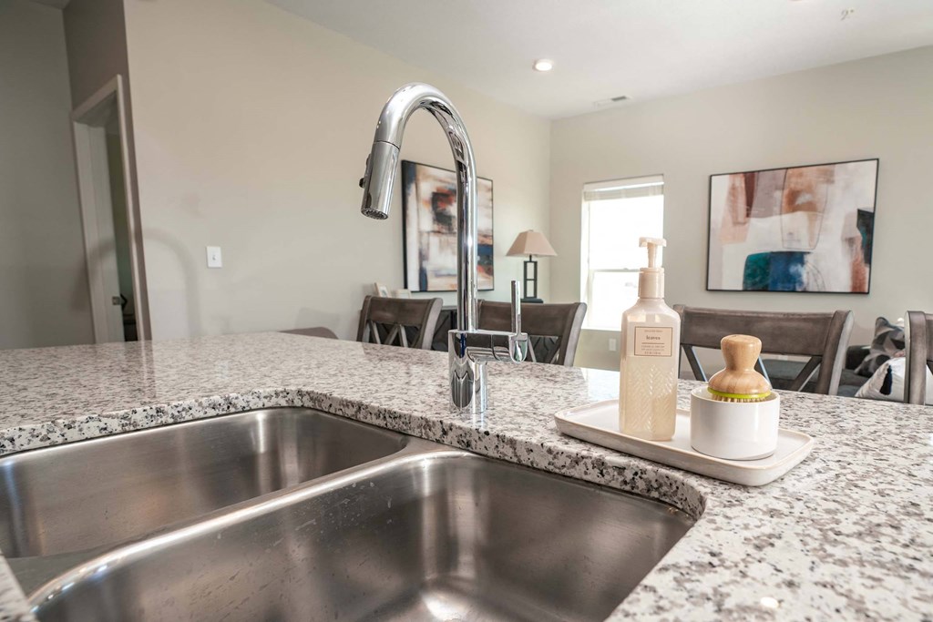 A modern kitchen with a granite countertop and stainless steel sink.
