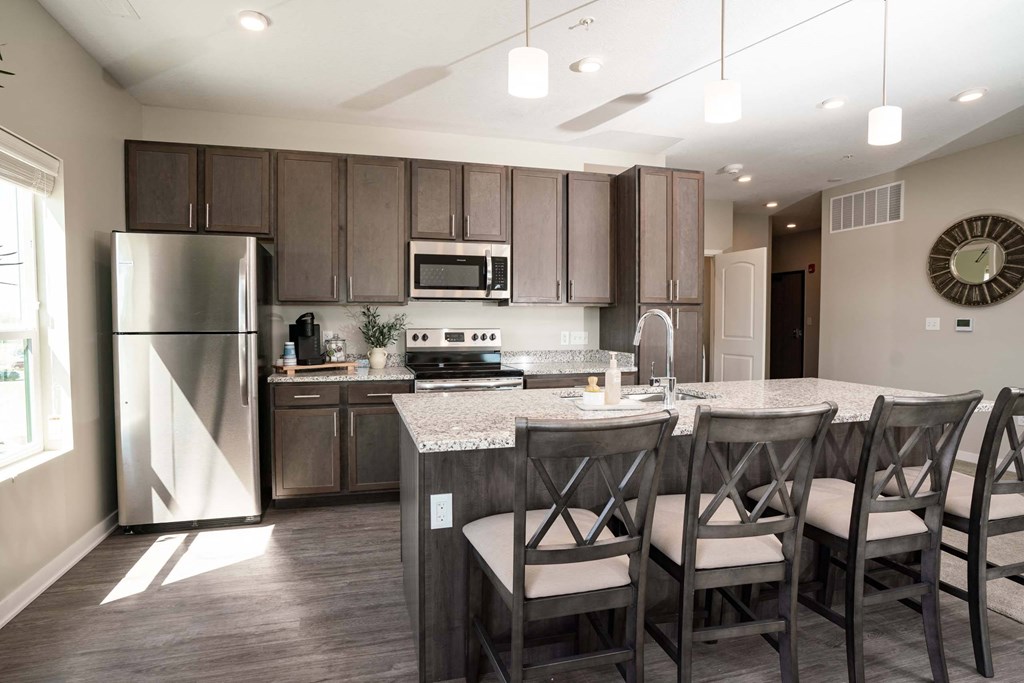 A modern kitchen with a refrigerator, microwave, oven, and sink.