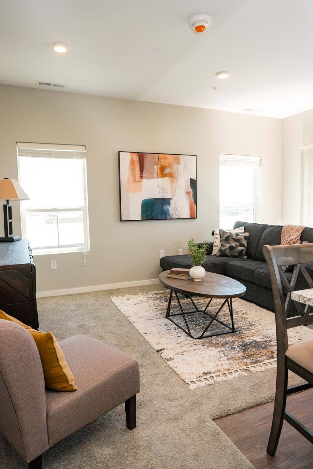 A living room with a grey couch, a coffee table, and a painting on the wall.