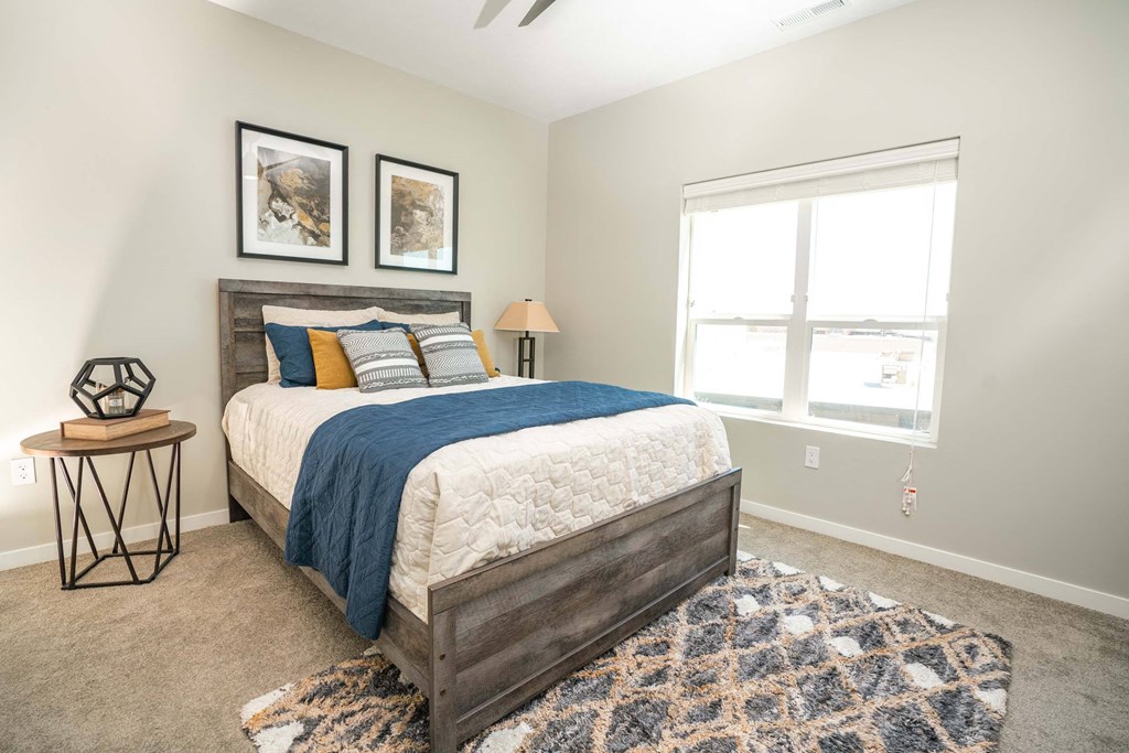 A bedroom with a bed, a table, and a rug.