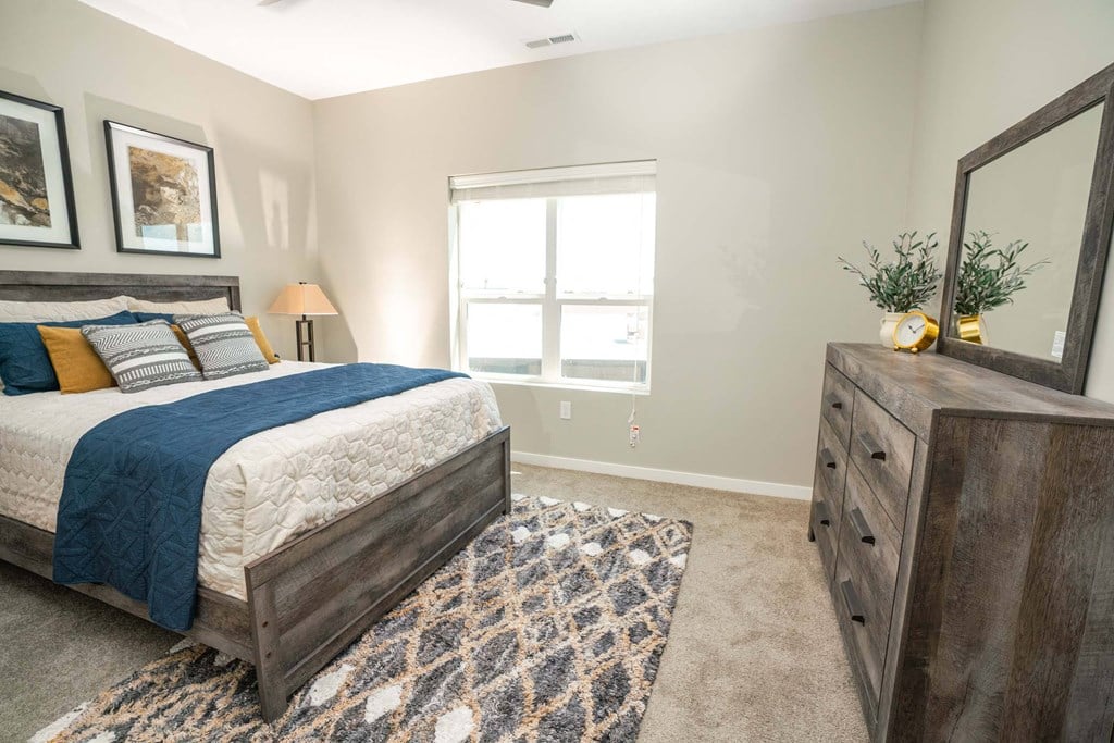A bedroom with a bed, dresser, and window.