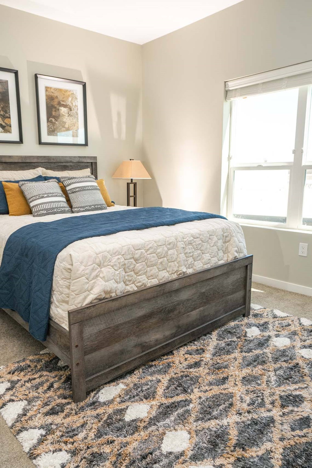 A bed with a blue blanket and pillows is in the center of the image.