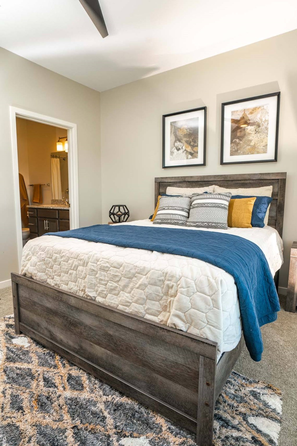 A bed with a blue blanket and pillows is in the foreground of a room.