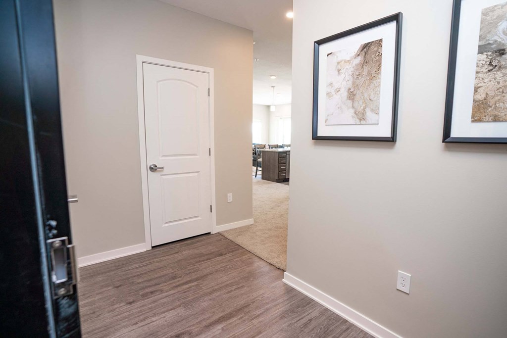 A hallway with a white door and two pictures on the wall.