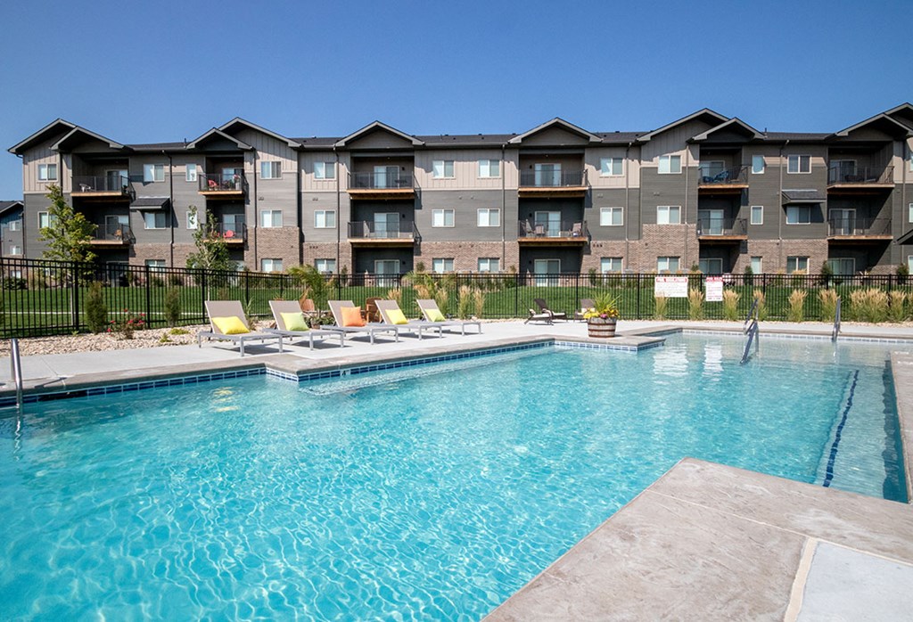 A large swimming pool in front of apartment buildings.