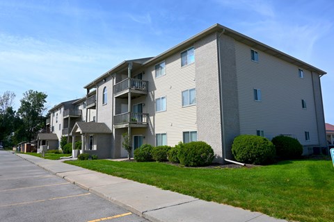 Apartment building with a parking lot in front.